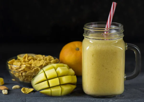 Batidos de frutas tropicales, miel y cereales en la mesa de madera negra . — Foto de Stock