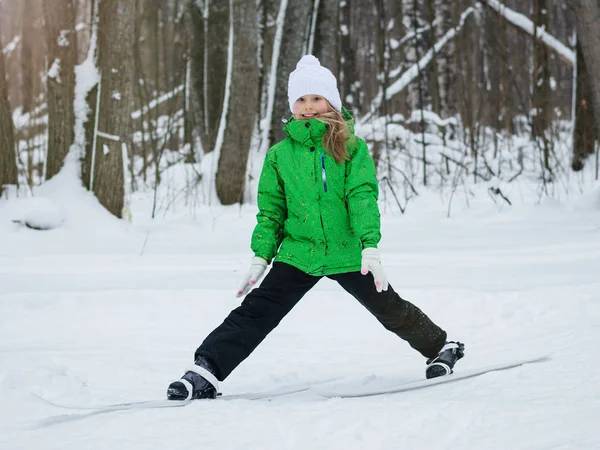 Flicka i overaller utför stretching övningar på skidor. — Stockfoto