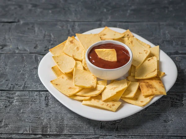 Mexican tortilla chips in a bowl with sauce and mustard on the table on a white plate with sauce in the center. — Stock Photo, Image