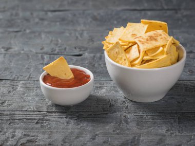 Rustik masada soslu bir kasede Meksika tortilla cips.