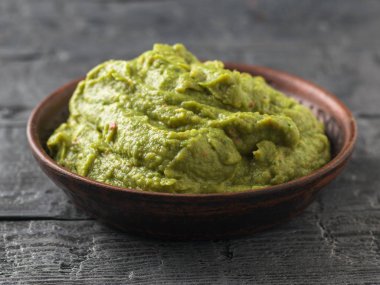 Taze guacamole bir kil kase karanlık bir rustik tablo yaptı. Çiğ gıda.