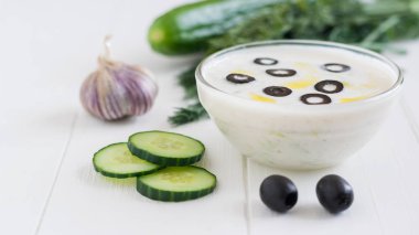 Taze sarımsak Beyaz ahşap bir masa üzerinde bir cam kase cacık yaptı.