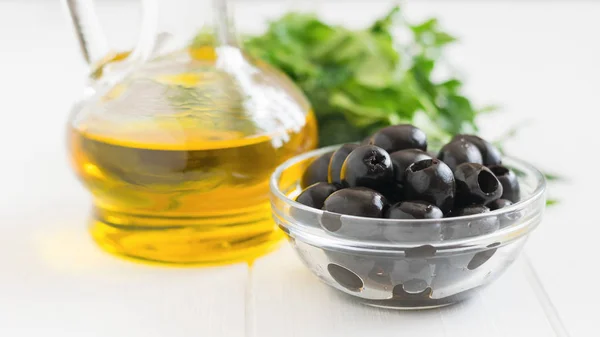 Zaitun, herbal dan sebotol minyak zaitun di atas meja putih . — Stok Foto