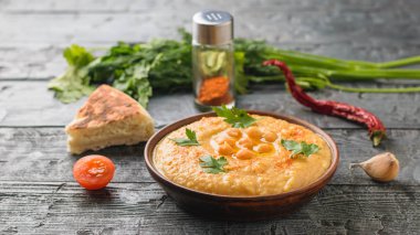 Kil kase taze Humus, bir parça pide ve koyu ahşap bir masa üzerine dilimlenmiş domates ile.