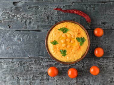 Kil kase taze humus ve koyu ahşap bir masa üzerinde domates ile. Üstten Görünüm.