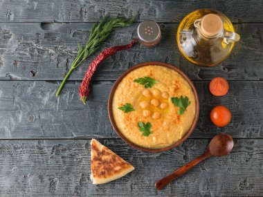 Taze Humus, tahta kaşık, bir parça silindir Mini değirmenler, ahşap bir masa üzerinde domates. Üstten Görünüm.