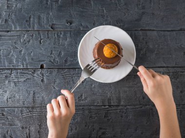 Çocuk bir taze tatlı ahşap bir masa üzerinde beyaz bir fincan bir bıçakla keser. Üstten Görünüm.