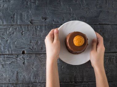 Çocuk beyaz bir bardak taze pasta ile ahşap bir masa üzerinde tutar..