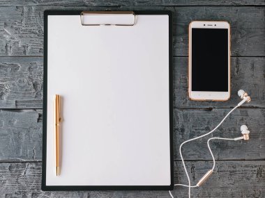 Defter kalem, smartphone ve koyu ahşap bir masa üzerinde kulaklık ile. Üstten Görünüm.