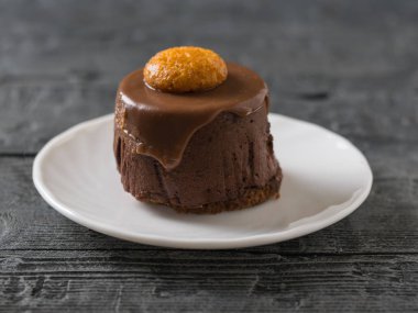 Karanlık bir rustik masada beyaz bir tepside kek.