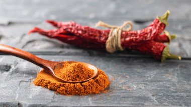 Tahta kaşık toz biber ve ahşap masa üzerinde üç biber ile.