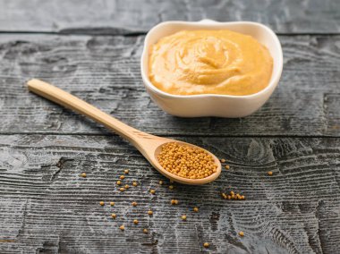 Kaşığı hardal tohumu ve karanlık rustik masada hardal soslu kase ile.
