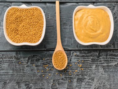 Hardal soslu kase, hardal tohumu ve karanlık rustik masa kaşık kase.