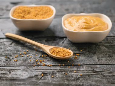 İki kase ve iki kaşık siyah bir tablo üzerinde tohum ve hardal soslu.