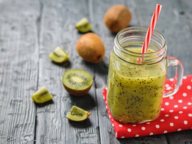 Kupa ile taze yapılmış kivi güler yüzlü bir rustik siyah masada kırmızı bir bez üzerinde.