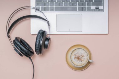 Headphones on the laptop and a Cup of coffee with cinnamon on a light background. Job.
