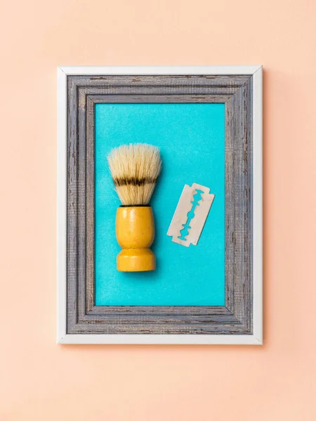 Una lama di rasoio e spazzola da barba in una cornice sulla parete di corallo. Il concetto di cura del corpo. Igiene . — Foto Stock