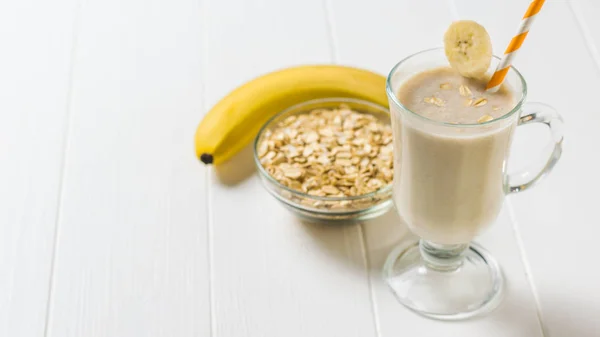 Pisang matang, oatmeal dan smoothie pisang di atas meja kayu putih. Vegetarian smoothie . — Stok Foto