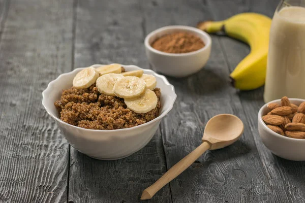 Bubur Quinoa dengan pisang dan susu almond di atas meja kayu . — Stok Foto