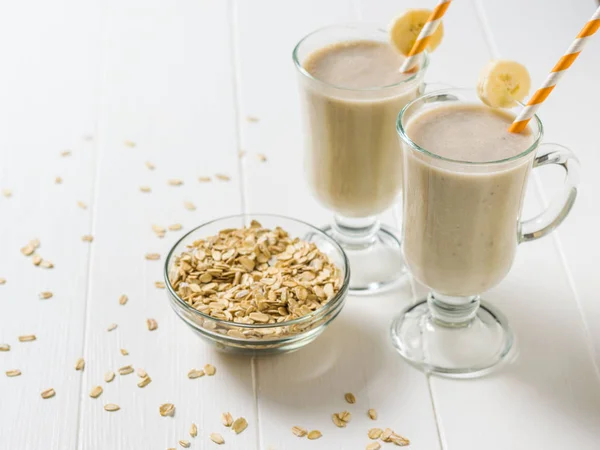 Pisang smoothie dan oatmeal tersebar di meja kayu putih. Vegetarian smoothie . — Stok Foto