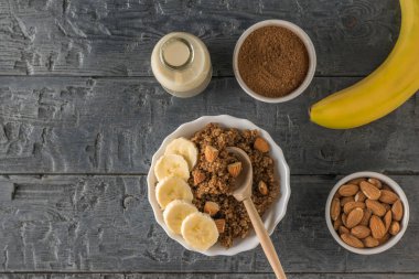 Siyah ahşap bir masada muz ve badem sütlü kinoa lapası. Düz yatıyordu.