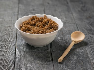 Tahta bir kaşık ve ahşap bir masada beyaz bir kase kinoa lapası..