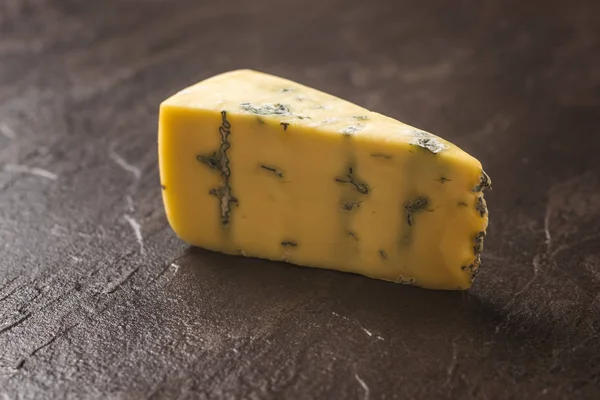 Um pedaço de queijo fresco com mofo azul em um fundo de pedra. Delicadeza de queijo . — Fotografia de Stock