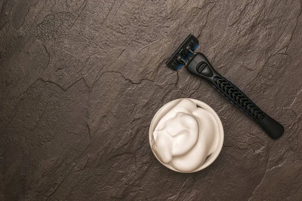 Men\'s hand razor and shaving foam on a stone background. Flat lay.