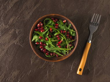 Arkaplanda nar tohumu, roka ve çatal bulunan kil kasesi. Düz yatıyordu.