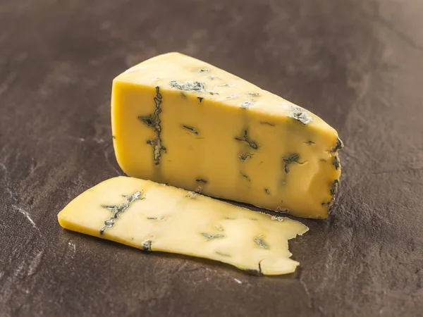 Um pedaço de queijo fresco com mofo azul sobre um fundo de pedra escura. Delicadeza de queijo . — Fotografia de Stock