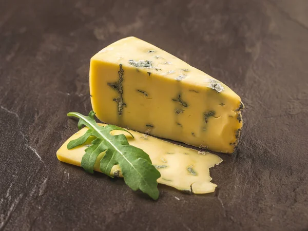Queso con moho azul y una ramita de rúcula sobre un fondo de piedra. Delicias de queso . —  Fotos de Stock