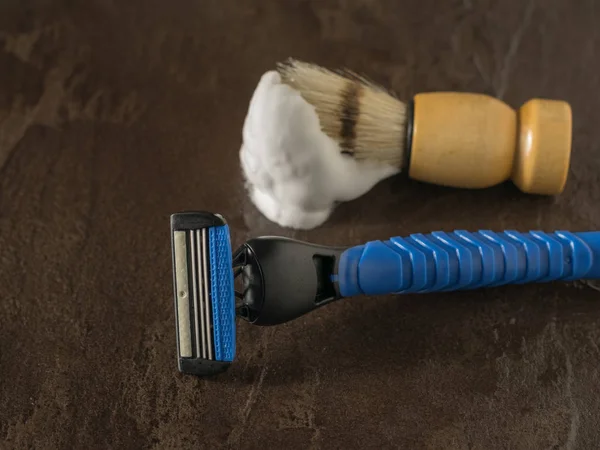 Shaving brush with shaving foam and razor blue on a stone background. Flat lay.