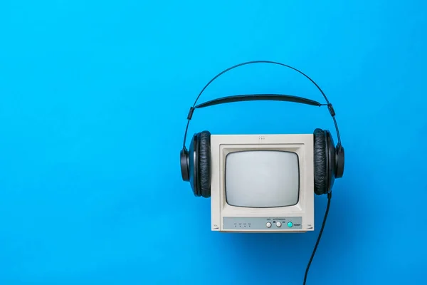 Vintage TV with kinescope with headphones on a blue background.