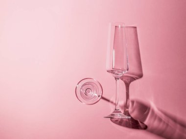 Pembe arka planda sert gölgeli iki cam bardak..