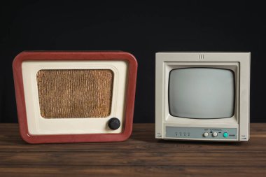 Retro CCTV monitörü ve antika radyo ahşap masa üzerinde siyah arkaplan.