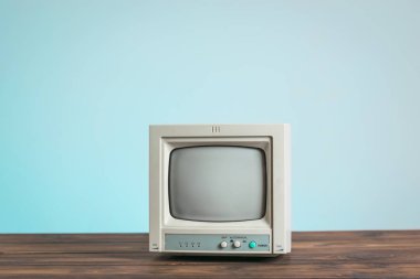 Mavi arka plandaki ahşap bir masanın eski monitörü..