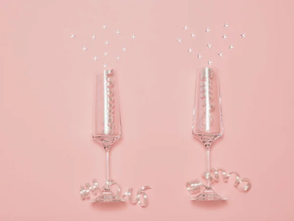 Dos copas de cristal con lentejuelas imitando salpicaduras de champán sobre un fondo rosa . — Foto de Stock