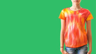 Tişörtlü bir kız. Çerçevenin sağ tarafında yeşil bir arka planda kravat boyası var..