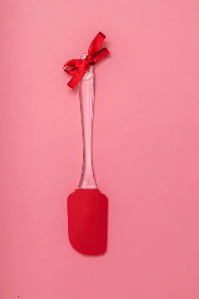 Espátula de cocina roja con cinta roja sobre fondo rosa. Puesta plana . — Foto de Stock