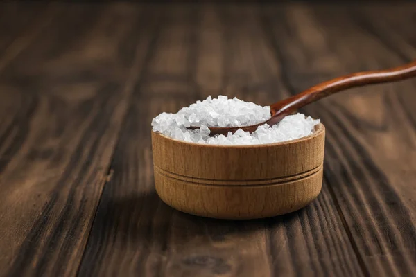 Copo de madeira e colher com sal grosso em uma mesa de madeira . — Fotografia de Stock