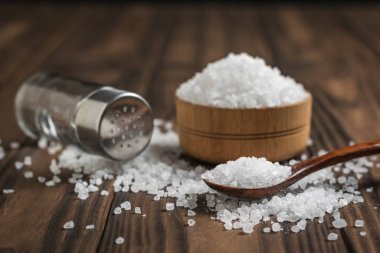 Glass salt shaker, wooden Cup and spoon on the table. clipart