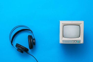 Kablolu siyah kulaklıklar ve mavi arka planda küçük bir retro monitör..