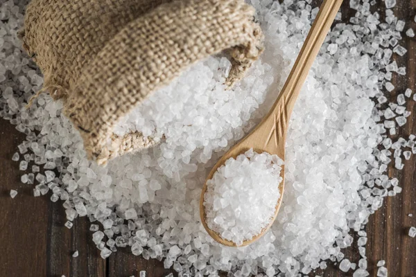 En vält säck och en träsked med utspritt salt på bordet. — Stockfoto