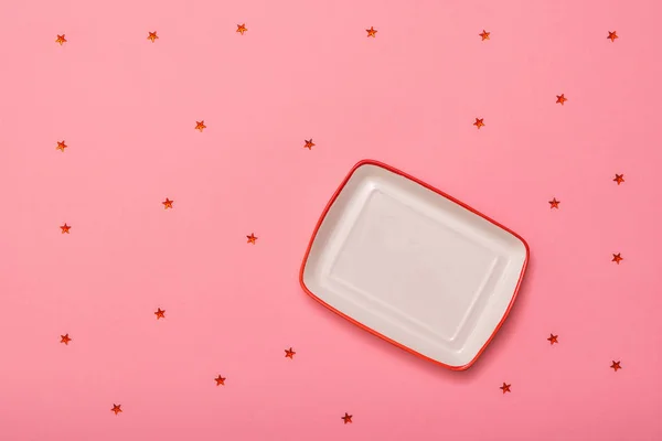 Plato rectangular blanco con borde rojo sobre fondo rosa con estrellas. Puesta plana . — Foto de Stock