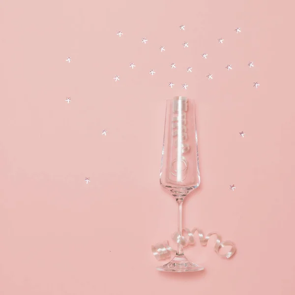 Copa de champán con lentejuelas brillantes sobre un fondo festivo brillante . — Foto de Stock