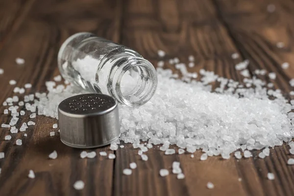 Large sea salt scattered on a wooden table.