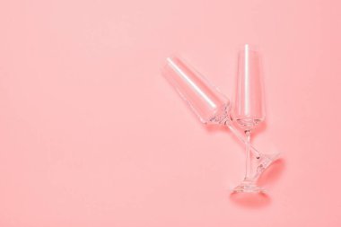 Pembe arka planda uzun bacakları olan iki güzel kristal bardak..