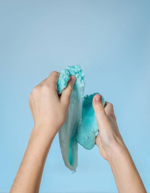 Mavi arka planda bir çocuğun sağ elinde mavi balçık..