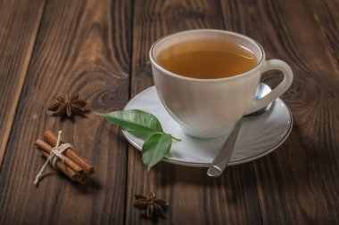 Tahta bir masada tarçınlı beyaz bir fincanda taze çay..