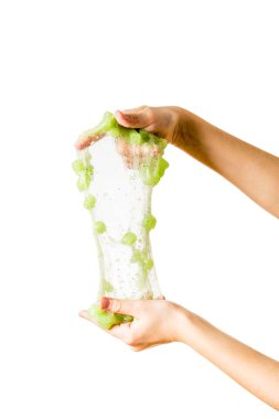 Bir çocuk yeşil bir balçığı, beyaz bir arka planda izole edilmiş katkı maddeleriyle gerer..